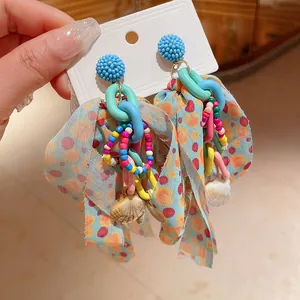 Detailed view of colorful bow earrings featuring steel needles and decorative shell pendants