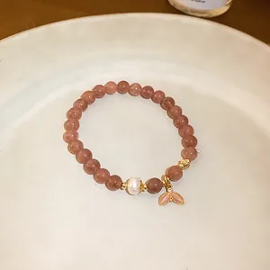 Macro view of strawberry quartz beaded bracelet with pearl and mermaid tail charm