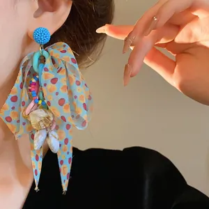 Close-up detail of a colorful beaded bow earring with shell charms, perfect for vacation style.
