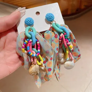 Detailed view of bohemian earrings with colorful beads, fabric ribbons, and seashell charms