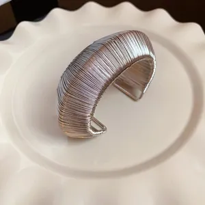 Macro detail showing the intricate silver wire-wrapped woven texture of this wide metal cuff