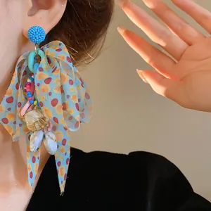 Close-up of a colorful bow earring with beads and shell charms in vacation style