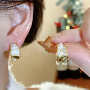 Primo piano macro di orecchini vintage francesi dorati con zircone verde e perle
