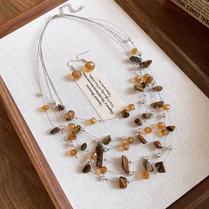 Close-up of multi-layer tiger eye beaded necklace and earring set on a wooden tray