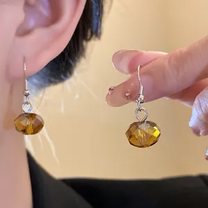 Close-up of amber faceted bead earrings showing detailed texture and wear effect.