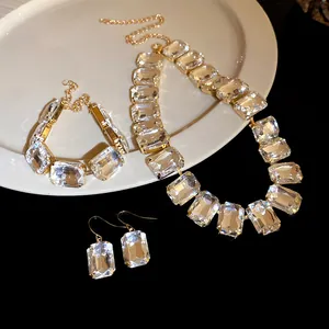Nahaufnahme des Schmucksets mit klaren Kristallen im Smaragdschliff und goldenem Finish.