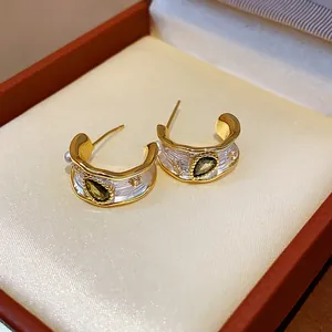 Dettaglio degli orecchini dorati con zircone verde e perle nella propria scatola.