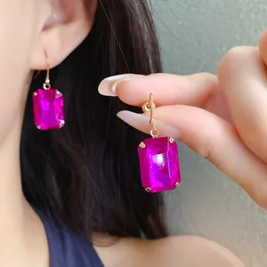 Detailansicht eleganter, leuchtend pinker rechteckiger Edelstein-Ohrhänger an einem Model