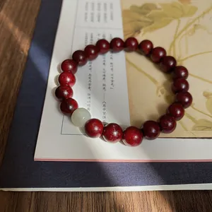Armband im neuen chinesischen Stil mit dunkelroten Holzperlen und einer blassgrünen Jadetropfen.