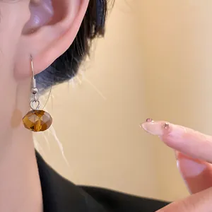 Detailed view of a vintage amber-colored faceted bead drop earring on a model's ear