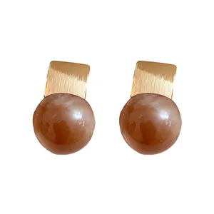 Elegant resin stud earrings featuring golden brushed metal accents and amber spherical beads