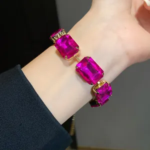Nahaufnahme eines eleganten goldfarbenen Armbands mit großen magentafarbenen Kristallen