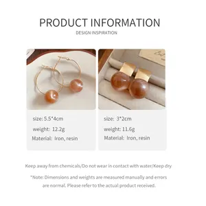 Macro view of amber resin earrings with detailed size, weight, and material specifications.