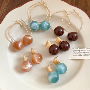 Variety of dopamine candy-colored resin earrings in stud and hoop styles on a plate