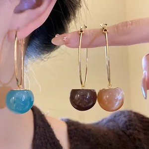 Detailed macro view of colorful resin ball hoop earrings in blue and brown shades