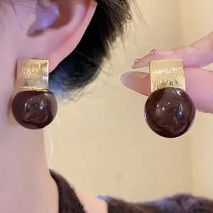 Close-up of candy color resin drop earrings with gold square accents