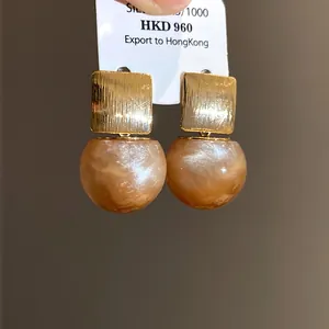 Detail of resin ball earrings with gold-toned brushed metal square top and 925 silver needles