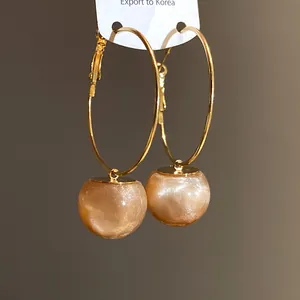 Detailed close-up of shimmering peach resin hoop earrings in sweet Korean style