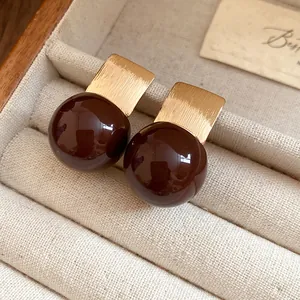 Close-up of vintage brown resin earrings with gold-tone brushed metal finish