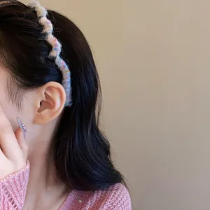 Side view detail of a colorful yarn-wrapped wavy headband worn by a model