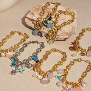Detailed macro view of gold and silver ocean bracelets with sea shell and pearl charms