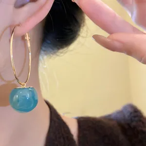 Detailed view of a stylish gold hoop earring with a marbled blue resin drop bead