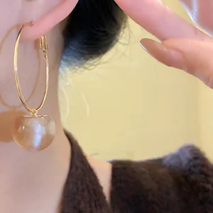Close-up view of golden hoop earrings featuring a shimmering champagne resin bead charm.
