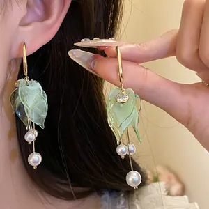 Close-up detail of elegant green leaf tassel earrings with white pearls and zircon
