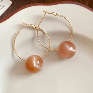 Close-up of golden hoop earrings featuring large translucent candy-colored resin beads