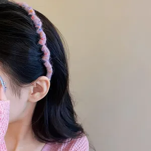 Detailed macro view of a pink wavy yarn-wrapped headband showcasing soft wool texture