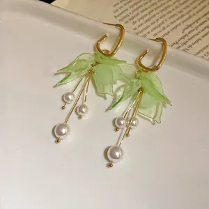 Detailed view of elegant green flower petal earrings with dangling white pearl tassels