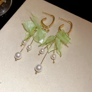 Detail view of light green petal earrings with elegant pearl tassels and gold finish