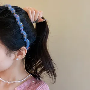 Close-up of a stylish blue wool wrapped wave headband worn by a model in detail.