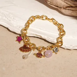 Close-up view of a gold ocean-themed charm bracelet featuring star and shell pendants.
