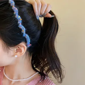 Close-up detail view of the stylish blue yarn-wrapped wavy headband on model's hair