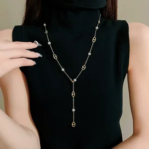 Elegant gold-plated pig nose link necklace with white pearls on a black turtleneck.