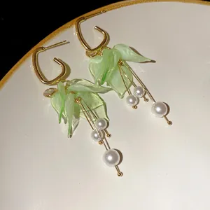 Detail of elegant green petal drop earrings with white pearl tassels and gold hoops