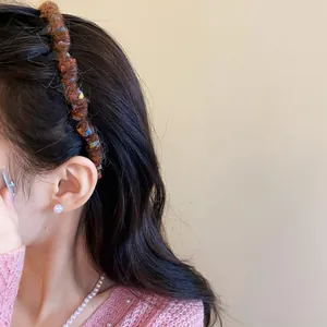 Close-up of autumn winter brown yarn wrapped wavy headband on model's hair.