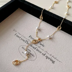 Detailed macro shot of a gold-plated pig nose link necklace with pearls on a vintage card