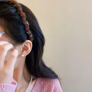 Macro shot of a brown wool-wrapped wave headband worn on a model with long dark hair.