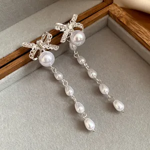 Primo piano di orecchini a fiocco in argento con lunghe nappe di perle bianche