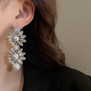 Elegant crystal flower and pearl drop earrings shown on model in a close-up view