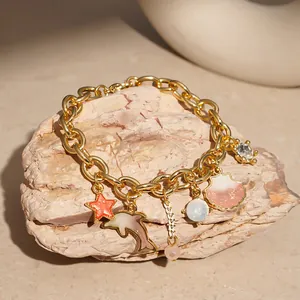 Close-up of ocean-themed gold charm bracelet with shell, dolphin, and starfish details