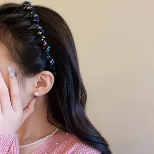 Close-up view of a stylish knitted wavy headband worn by a model with pearl jewelry