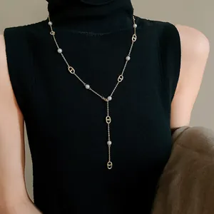 Detailed view of a gold-plated Y-shaped necklace with pearls and pig nose links on a model