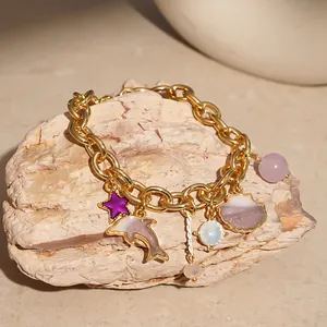 Close-up of a gold charm bracelet featuring marine charms like a dolphin and sea shell