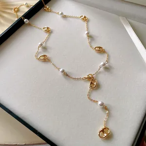 Close-up of gold-plated pig nose links and pearls on a French style long necklace