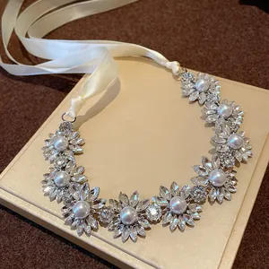 Detailed view of floral rhinestone and pearl necklace with elegant cream ribbon