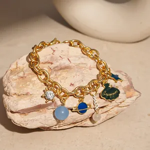 Close-up of gold ocean-themed bracelet with planet and shell charms on natural stone