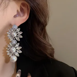 Close-up of exaggerated vintage floral crystal and pearl drop earrings on a model's ear